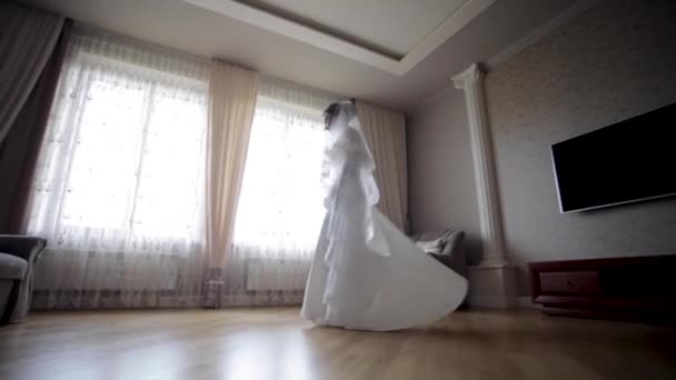 Hermosa novia girar alrededor en vestido de novia en casa. Fondo de ventana grande — Vídeos de Stock