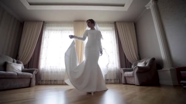 Hermosa novia girar alrededor en vestido de novia en casa. Fondo de ventana grande — Vídeos de Stock