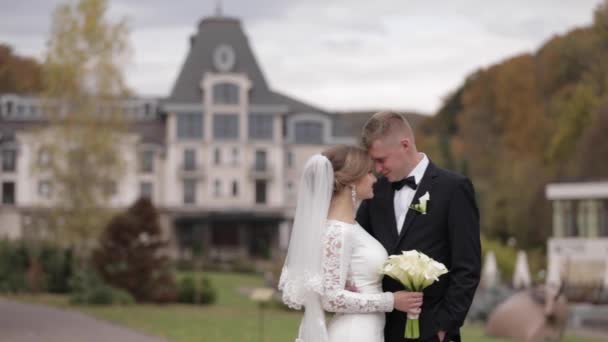 Happy newlyweds walking in the park. Elegant bride and handome groom outside — Stock Video