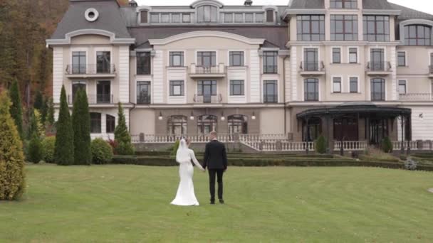 Visão traseira do noivo e da noiva caminhando para o palácio — Vídeo de Stock