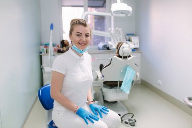Klinikte genç diş hekimi ekipman ve gülümseme önünde standı