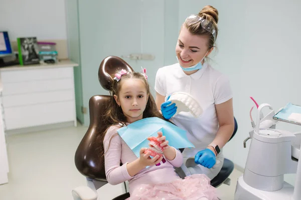 Dentist show to little girl how to wash teeth