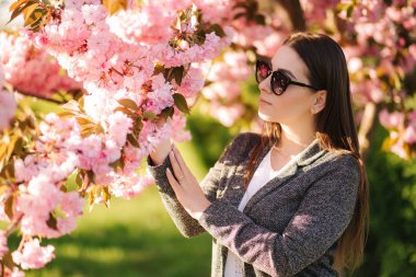 Güneş gözlüğü güzel kadın portresi pembe ağacın yanında standı