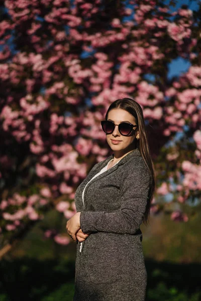 Bussines kvinna i kavaj och solglasögon står framför Pink Tree — Stockfoto
