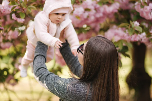 Side view of happy young mother holding baby girl in her hands and looking at her with love — Stock Photo, Image