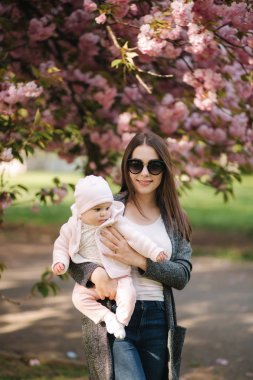 Güzel anne parkta elleri üzerinde onun bebek kız ile yürümek. Pembe arka plan