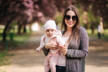 Güzel anne parkta elleri üzerinde onun bebek kız ile yürümek. Pembe arka plan