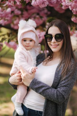 Güzel anne parkta elleri üzerinde onun bebek kız ile yürümek. Pembe arka plan