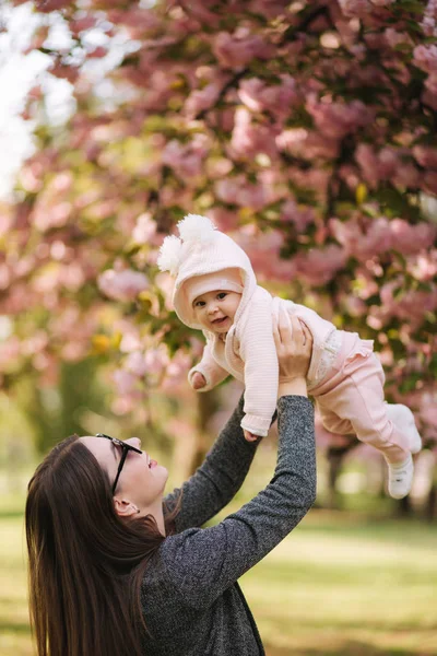 Pohled na tu šťastnou mladou matku, jak drží holčičku v dlaních a dívá se na ni s láskou — Stock fotografie