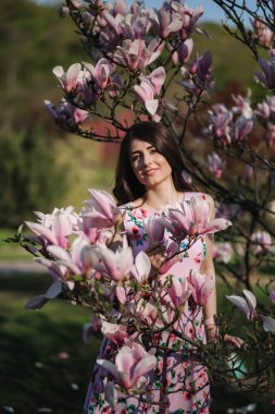 Sevimli kız güzel pembe manolya ağacı dışında standı. Muhteşem bayan