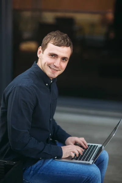 Feliz joven escribiendo algo en su portátil y sonreír — Foto de Stock