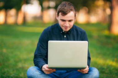 Programcı parkta dizüstü bilgisayarda çalışıyor. Bankta oturan adam