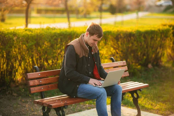 Jonge zakenman werkt in het park op de laptop — Stockfoto