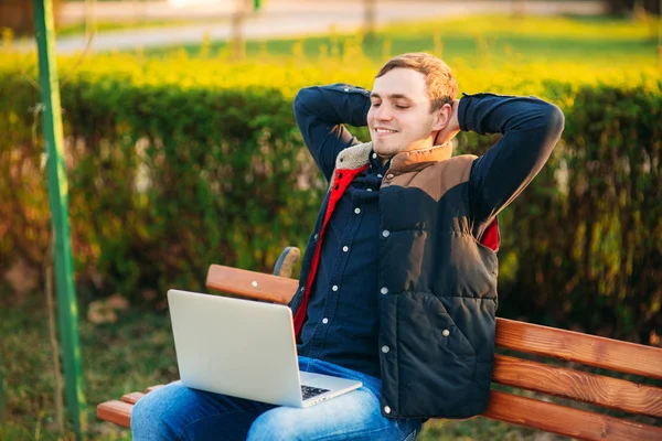 Young businessman finish work on his laptop in the park. Work in internet. Online business