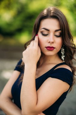 Akşam makyajı ile kadın yakın portre. Kadın gözlerini kapatın ve fahion slyle gösterir. Mavi ve yeşil bokeh backgrounf