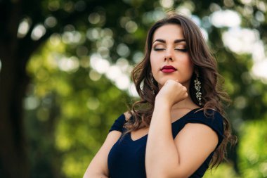 Akşam makyajı ile kadın yakın portre. Kadın gözlerini kapatın ve fahion slyle gösterir. Mavi ve yeşil bokeh backgrounf