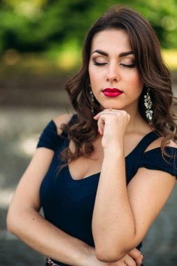 Akşam makyajı ile kadın yakın portre. Kadın gözlerini kapatın ve fahion slyle gösterir. Mavi ve yeşil bokeh backgrounf