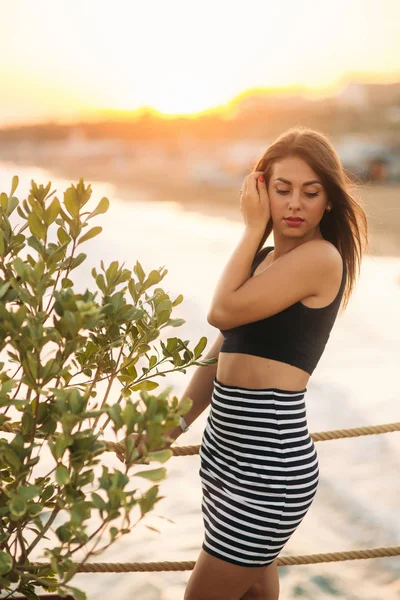 Приваблива дівчина, що йде пірсом біля моря під час заходу сонця — стокове фото