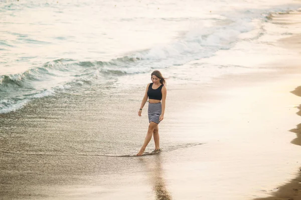 Mujer joven camina a lo largo de la costa en verano. Hermosa mujer sola — Foto de Stock