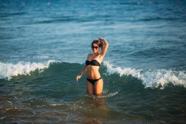 Güzel bayan belden derindenizin içindedir. Siyah bikini seksi kadın denizde dalgalar için bekleyin