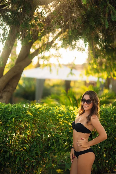 Mulher de biquíni preto stand by blossom tree — Fotografia de Stock