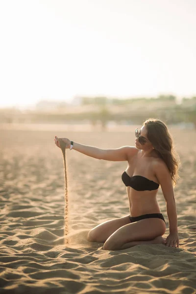 Сексуальная девушка загорает на пляже и играет с песком — стоковое фото