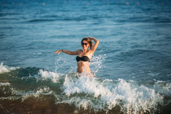 Hermosa dama es la cintura profunda en el mar. Mujer sexy en bikini negro esperar olas en el mar — Foto de Stock