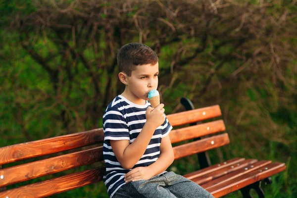 Egy kis fiú a csíkos póló kék fagylalt eszik. Tavasz, napsütés — Stock Fotó