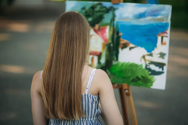 Вид ззаду красива світле волосся дівчина малює картину в парку — стокове фото