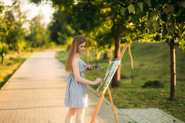 Blond włosy dziewczyna w sukience rysunek obraz w parku — Zdjęcie stockowe