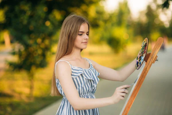 Hermosa artista chica está de pie en el parque y la celebración de la paleta con pinturas —  Fotos de Stock