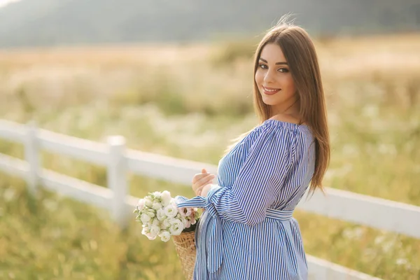 Retrato de mulher grávida bonita no campo segurando buquê e sorriso. Relaxe na natureza — Fotografia de Stock