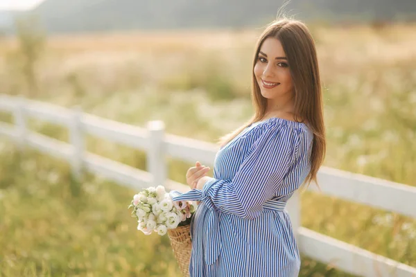 Porträt einer schönen schwangeren Frau auf dem Feld mit Blumenstrauß und Lächeln. Entspannung in der Natur — Stockfoto