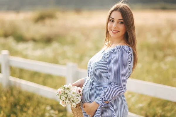 美丽的孕妇在外地拿着花束和微笑的肖像。在大自然中放松 — 图库照片
