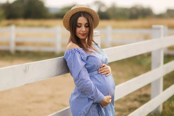 Bellissimo ritratto di donna incinta allegra in abito blu e cappello lavorato a maglia. Sorridi. — Foto Stock