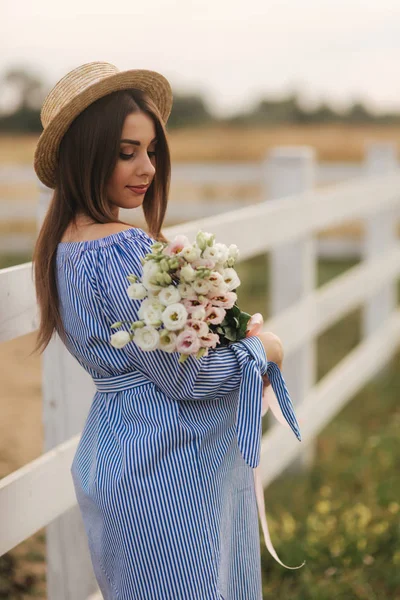 Encantadora mujer embarazada sostiene un ramo de flores. Feliz sonrisa de mujer. Futura madre en la naturaleza —  Fotos de Stock