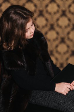 Güzel küçük bir kız kütüphanede kitap okuyor. Bir okul için hazırlanıyor