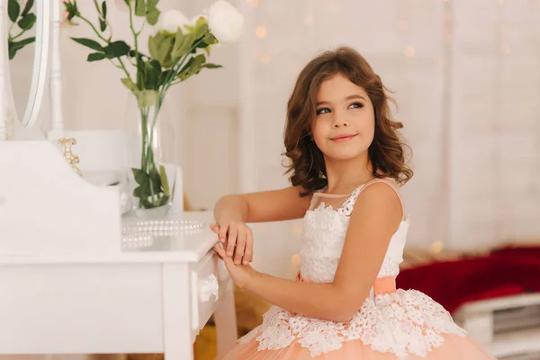 A menina senta-se ao lado do piano branco. Flores brancas no piano. Modelo menina em vestido bonito — Fotografia de Stock