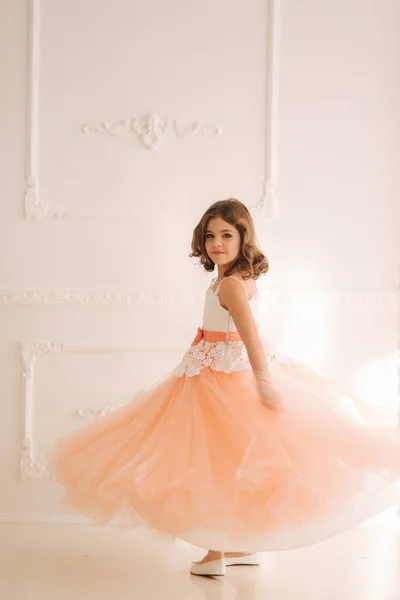 Fröhliche kleine Prinzessin in wunderschönem Kleid spaziert durch das große Studio. Drehung um — Stockfoto