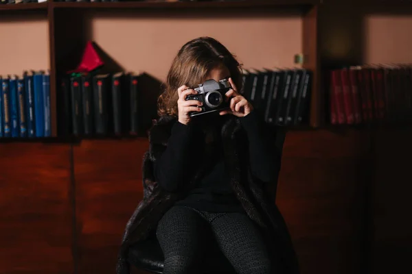 Little girl makes a photo on an old retro camera. Library — Stock Photo, Image