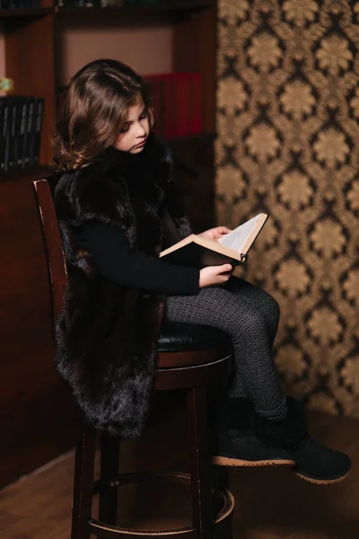 Hermosa niña está leyendo un libro en la biblioteca. Preparación para una escuela — Foto de Stock