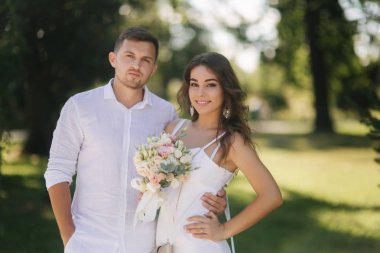 Damat ve gelin parkta yürüyüş onların düğün günü içinde. Yeni evliler birlikte vakit geçirmek. Yeni evli