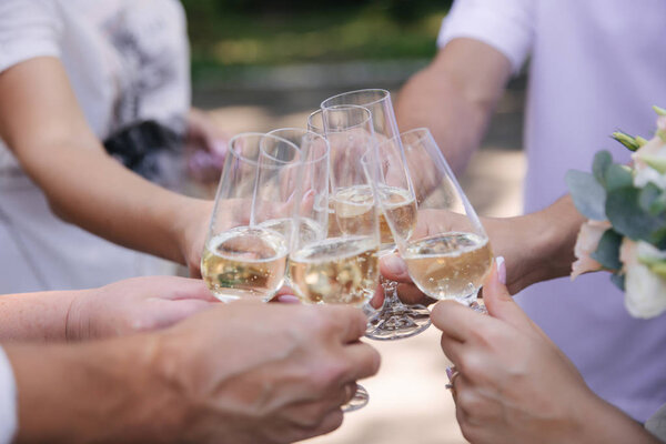 Groom hold a glass with champagne. Bouquet of flowers