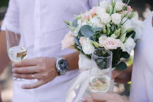Sposo tenere un bicchiere con champagne. Bouquet di fiori — Foto Stock