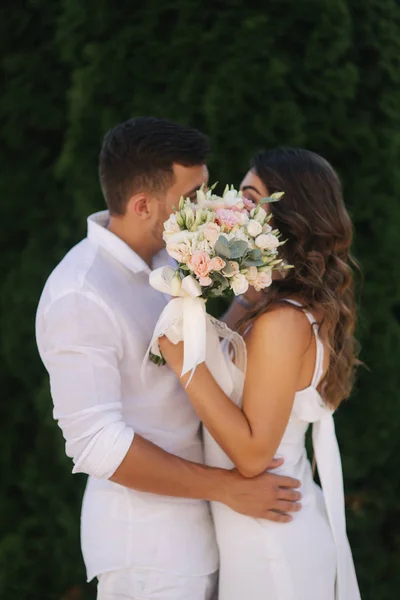 Muž žena polibek a skrýt v kytici. Svatební den — Stock fotografie