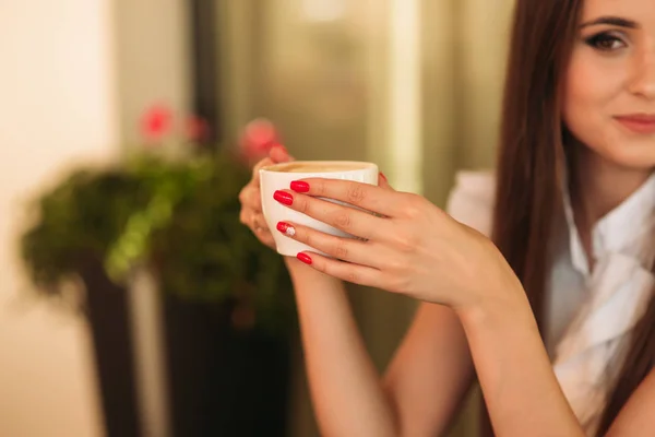 A fiatal lány tablettát használ és cappuccinót iszik. A lány a kávézóban. Boldog vonzó nő a teraszon — Stock Fotó