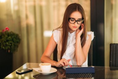 İş kadını çalışmak için tablet kullanıyor. Kafede çalışan güzel kadın