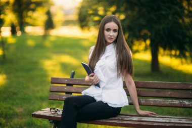 Dışarıda tabletli genç bayan öğretmen. Parktaki modern öğretmen. Kadın gözlük takıyor