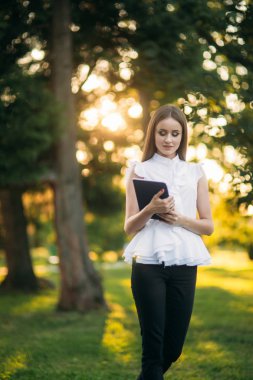 Dışarıda tabletli genç bayan öğretmen. Parktaki modern öğretmen. Kadın gözlük takıyor