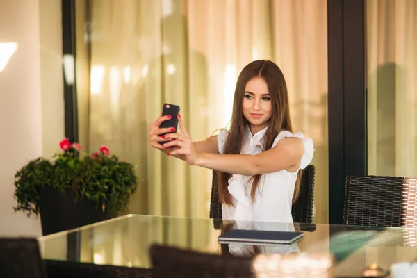 Hermosa mujer sentada en la cafetería y haciendo una selfie — Foto de Stock